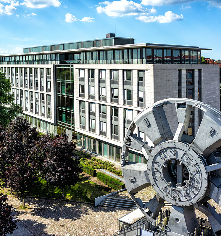 SAGA Unternehmenszentrale in Hamburg mit moderner Glasfassade und Tunnelbohrmaschinen-Skulptur im Vordergrund